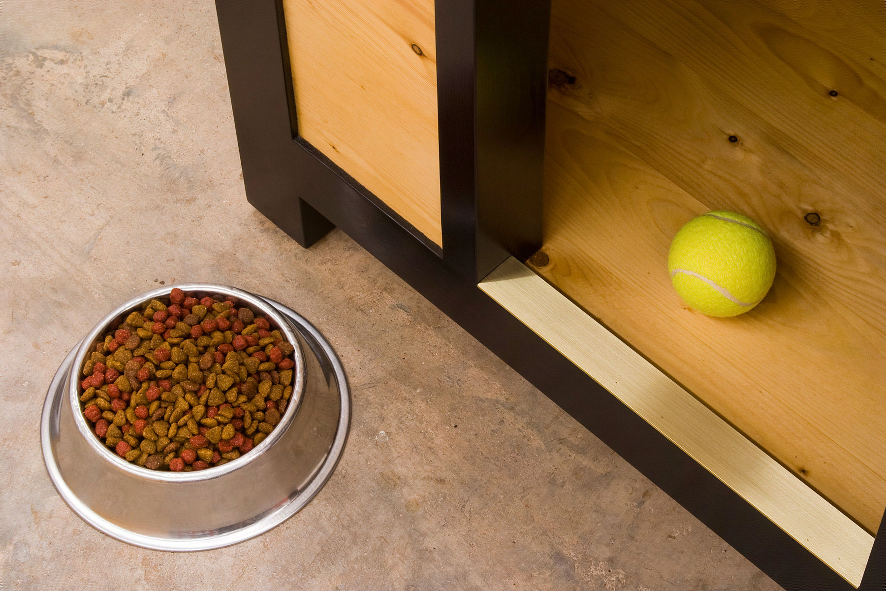 Lifestyle photo of BYST's dog house with dog food and a tennis ball