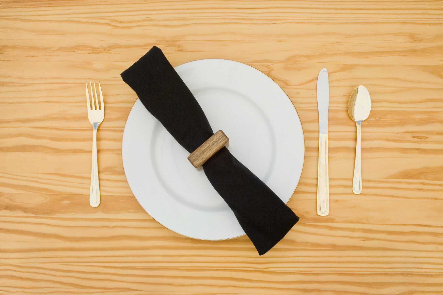 Place setting with a plate, flatware, and a napkin held by a BYST napkin ring in Gray-stained Hackberry