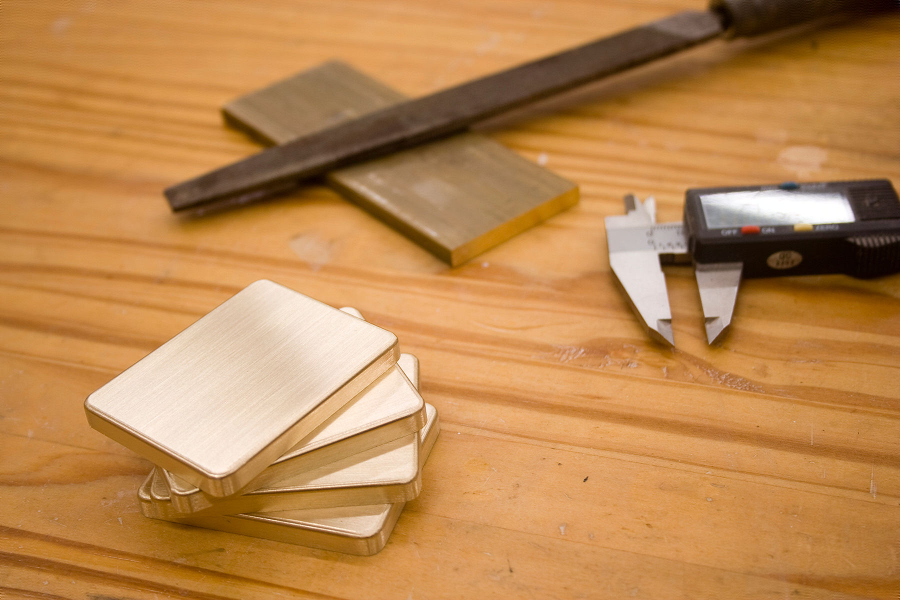 BYST's brass furniture pads stacked on a workbench